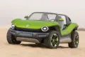 Grüner Volkswagen ID. Buggy ohne Dach und Türen steht auf Sand