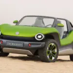 Grüner Volkswagen ID. Buggy ohne Dach und Türen steht auf Sand