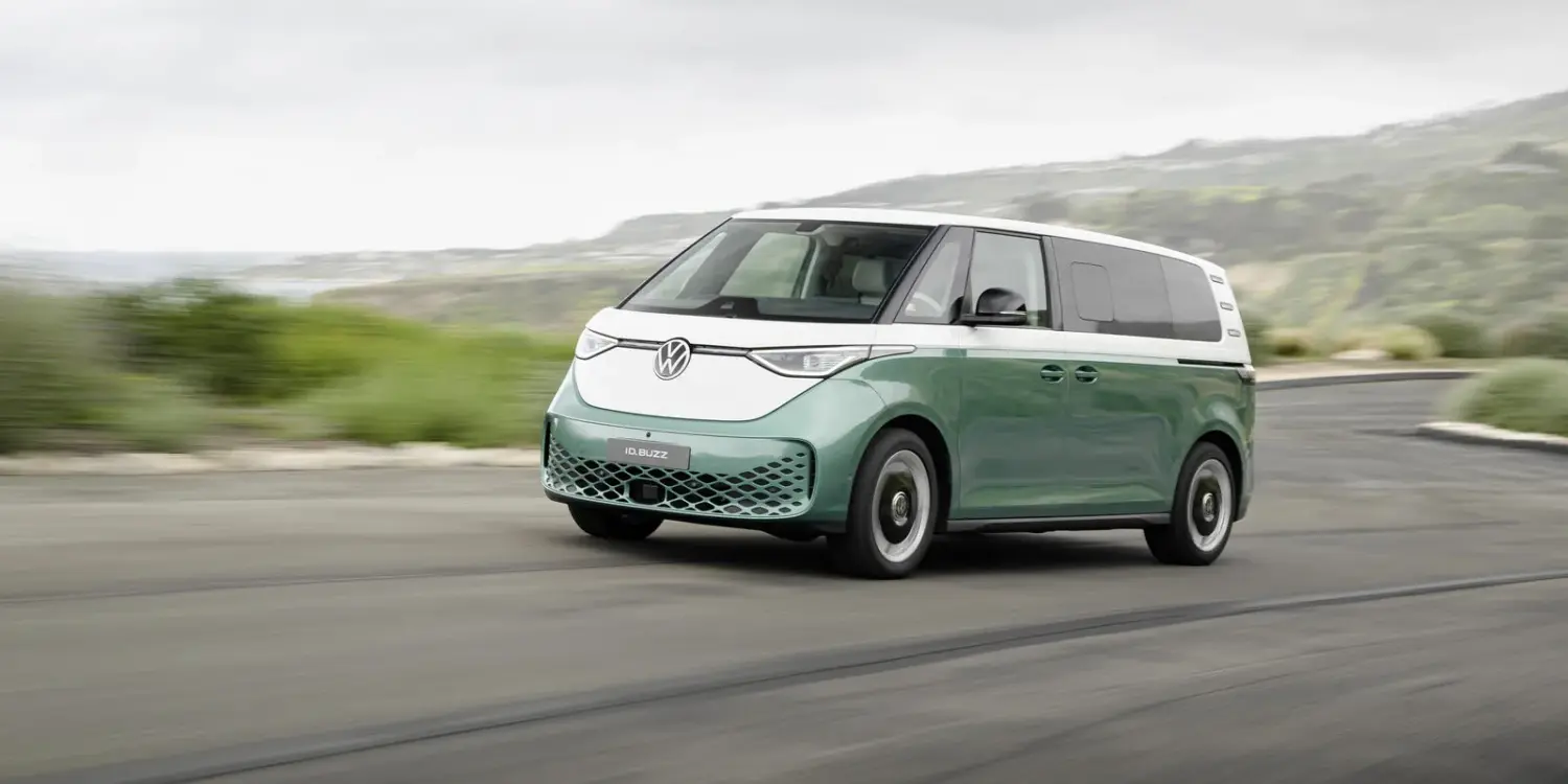 Volkswagen ID. Buzz mit langem Radstand in zweifarbiger Lackierung fährt auf einer Küstenstraße.