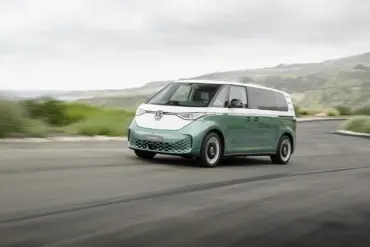 Volkswagen ID. Buzz mit langem Radstand in zweifarbiger Lackierung fährt auf einer Küstenstraße.