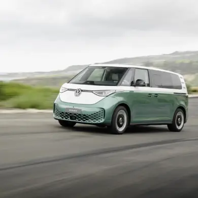 Volkswagen ID. Buzz mit langem Radstand in zweifarbiger Lackierung fährt auf einer Küstenstraße.