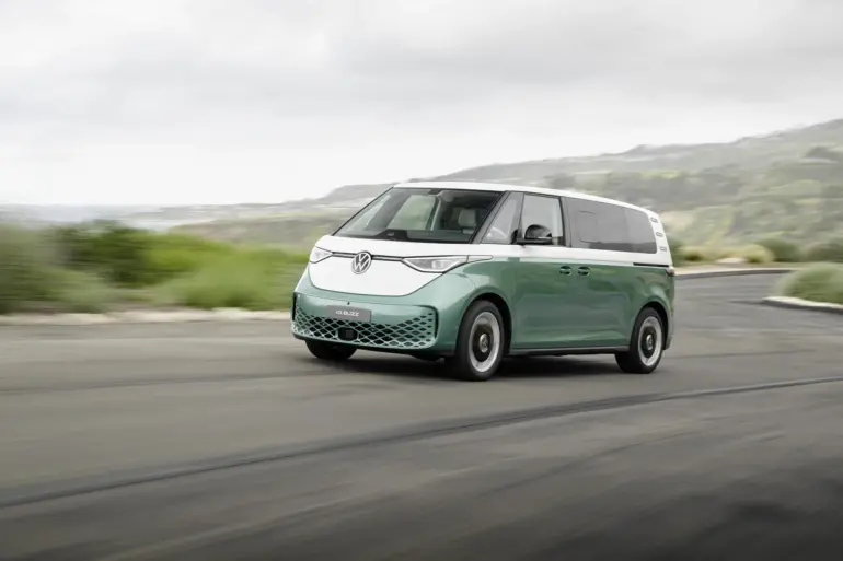 Volkswagen ID. Buzz mit langem Radstand in zweifarbiger Lackierung fährt auf einer Küstenstraße.