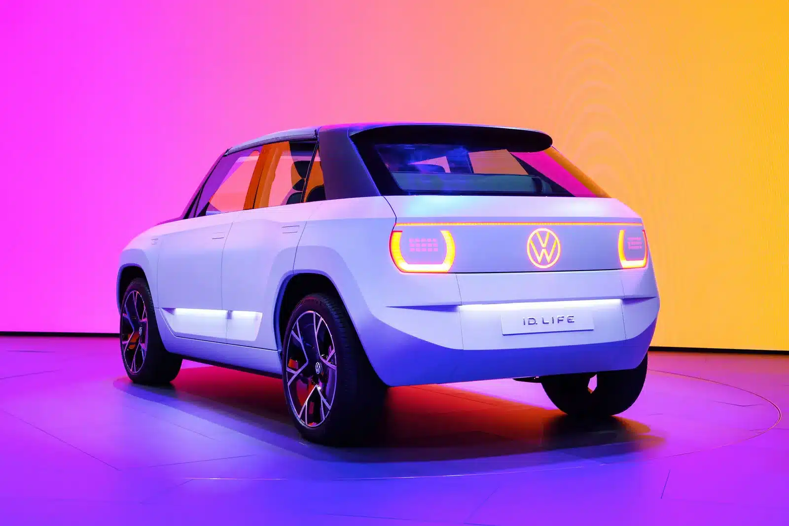 Rückansicht des Volkswagen ID. LIFE Konzeptfahrzeugs vor farbenfrohem Hintergrund auf der IAA Mobility 2021.