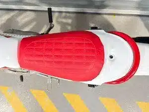 Rote, gesteppte Sitzbank einer Yamaha TY80 mit weißem Stahlrahmen, von oben fotografiert