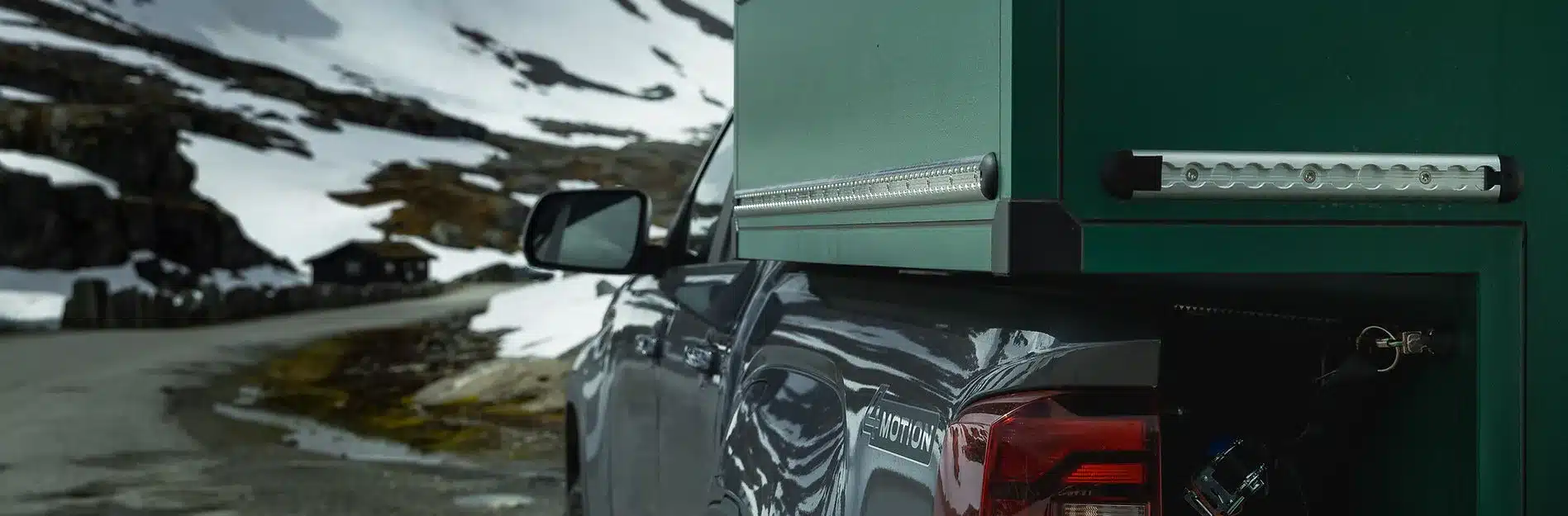 Pick-up mit montierter ZWO.EINZ Wohnkabine auf Bergstraße im verschneiten Gebirge