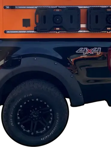 Seitenansicht eines schwarzen Pick-ups mit orangefarbener ZWO.EINZ Wohnkabine, montiert auf der Ladefläche.