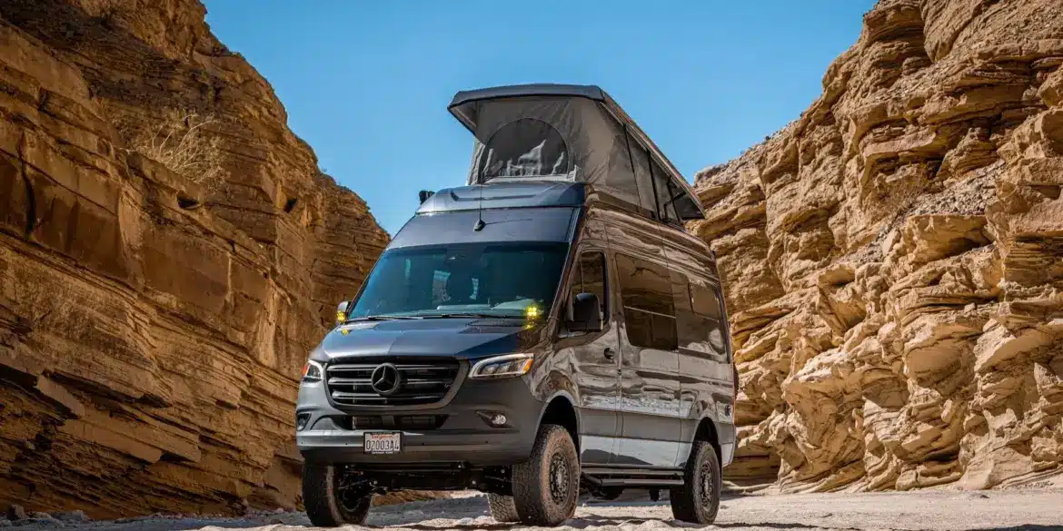 Mercedes Sprinter Kastenwagen PELE von Outpost Vans mit geöffnetem Aufstelldach und Offroad-Umbau, geparkt in einer felsigen Wüste.