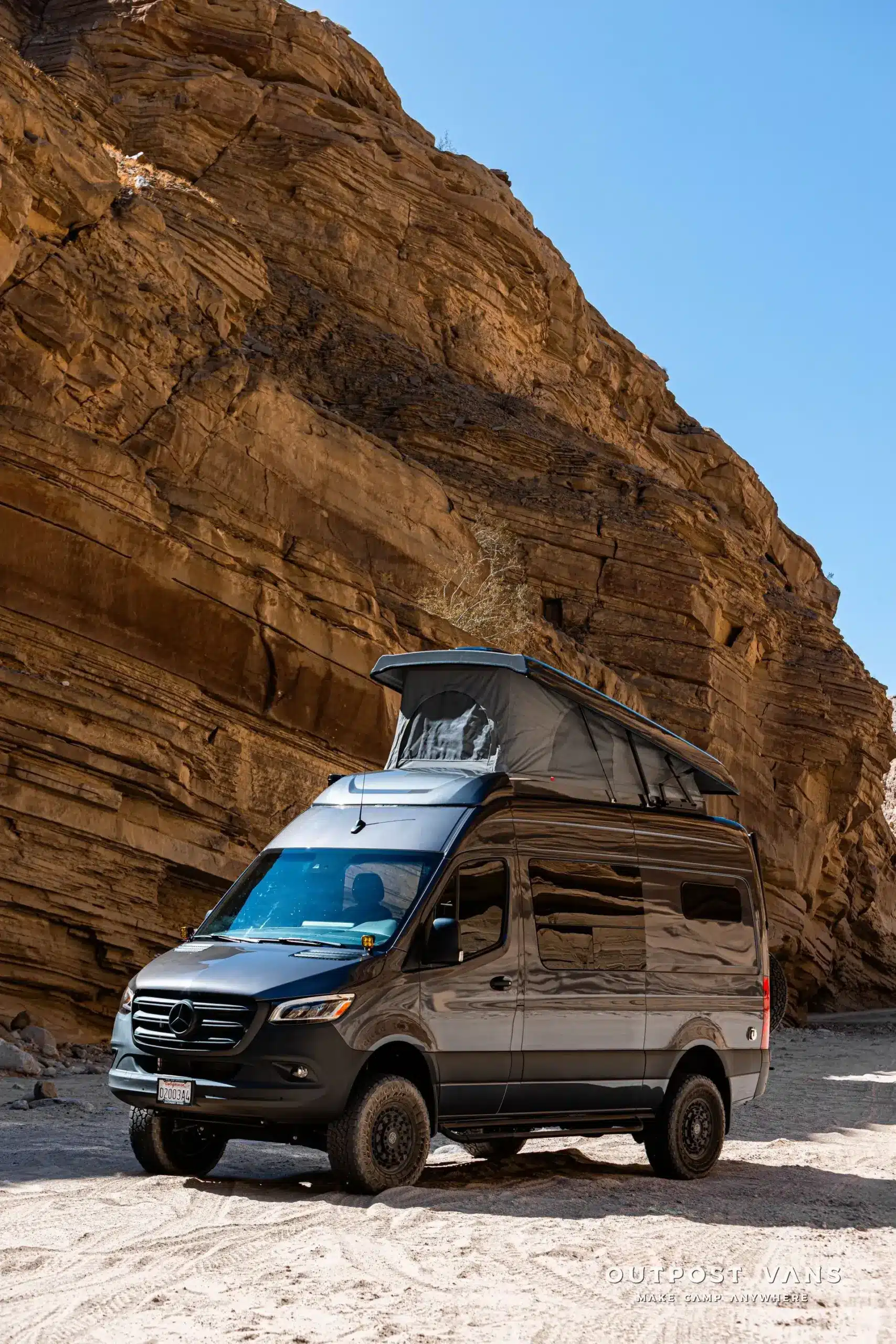 Mercedes Sprinter Kastenwagen PELE mit geöffnetem Aufstelldach und Offroad-Ausstattung, geparkt in einer sandigen Schlucht.