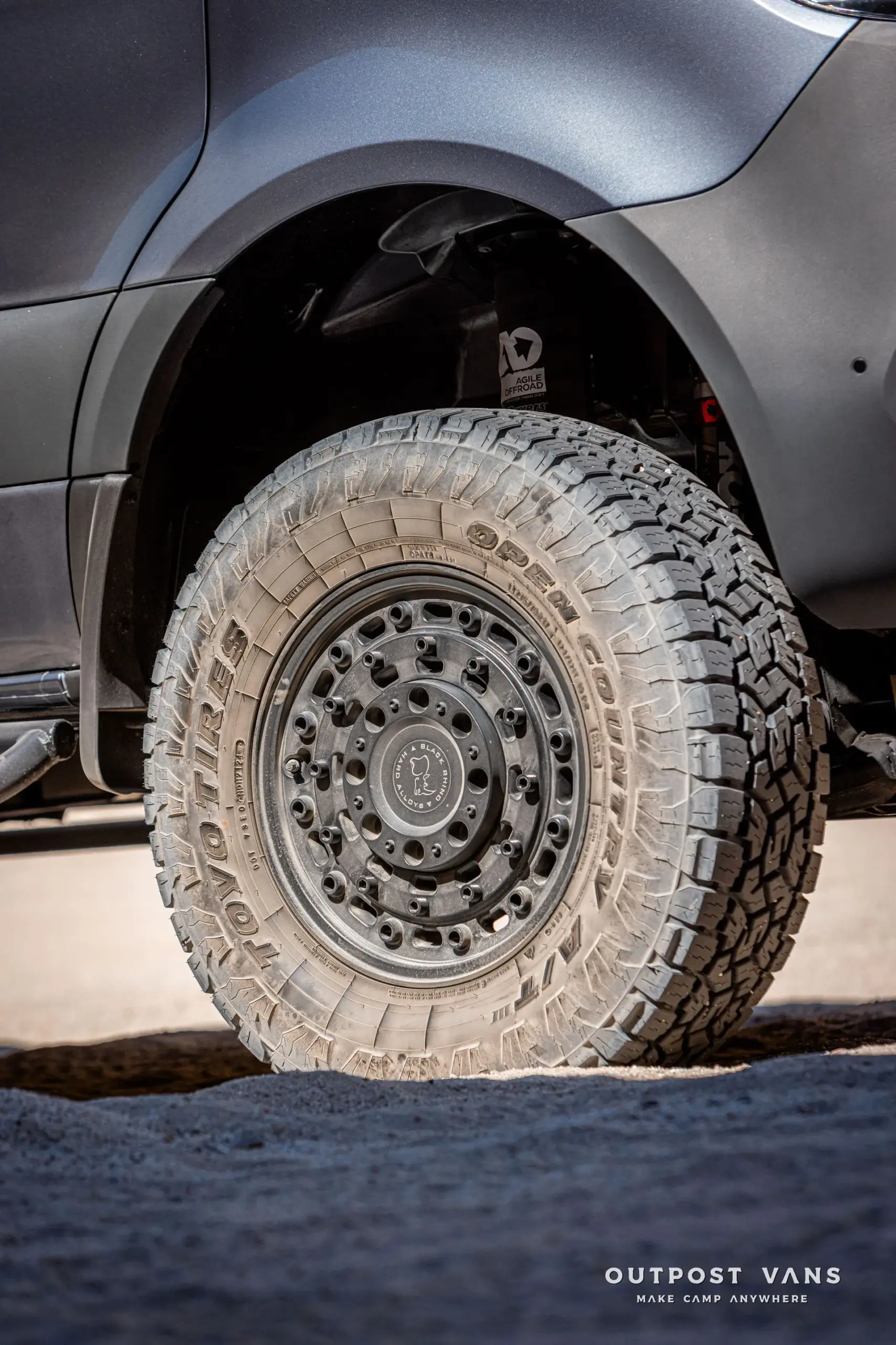 Nahaufnahme eines Offroad-Rads mit Grobstollenreifen und Black Rhino-Felge am Mercedes Sprinter PELE Camper, sichtbar das Agile Offroad-Fahrwerk.