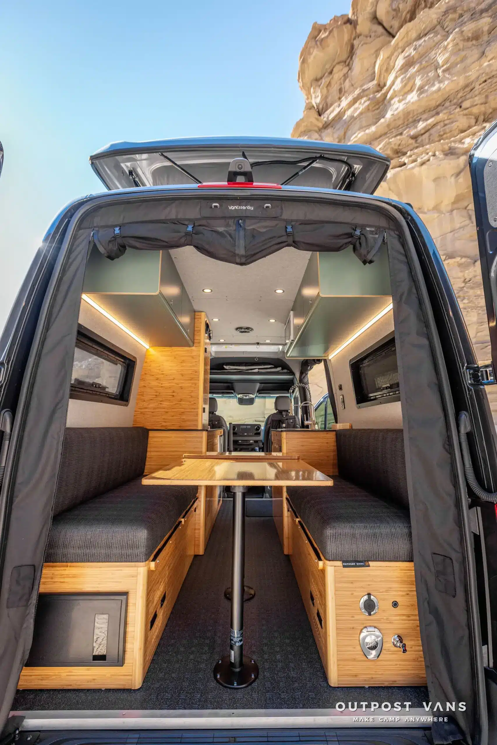Innenraum eines Mercedes Sprinter Kastenwagens im PELE-Ausbau mit Sitzbank, Tisch und Stauraum, aufgenommen von hinten mit offenem Heck.