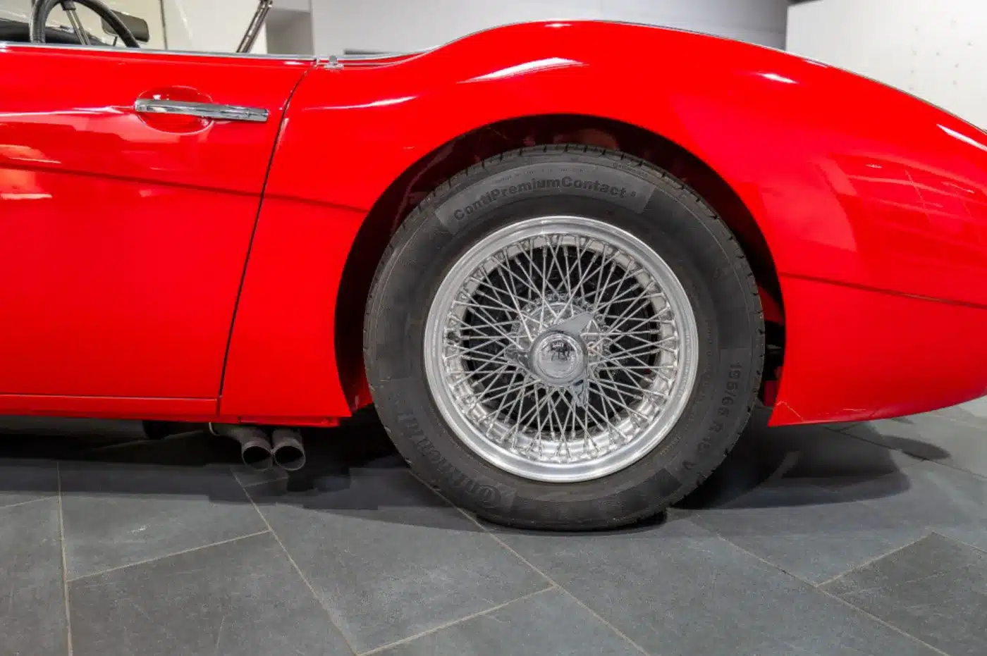 Seitliche Detailaufnahme eines roten Austin-Healey 3000 MK1 mit klassischem Speichenrad und Chromapplikationen