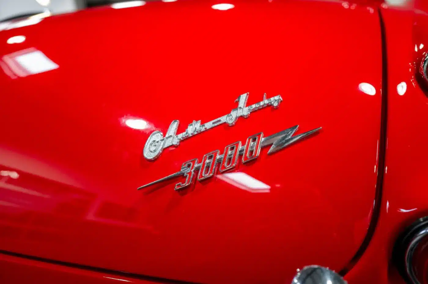 Verchromtes Austin-Healey 3000 Emblem auf rotem Lack eines Oldtimers