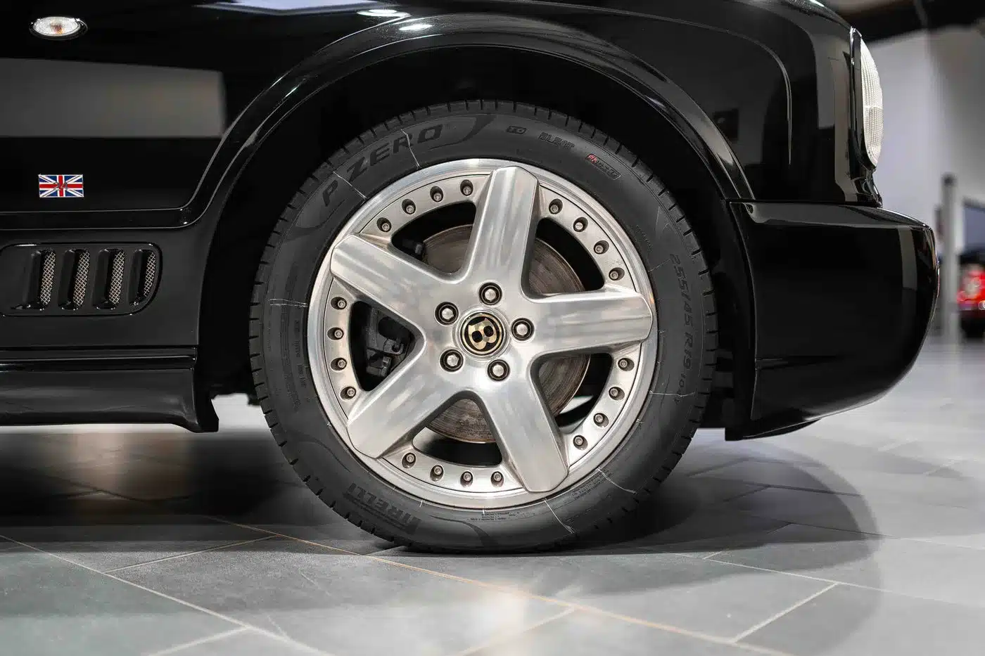 Nahaufnahme einer Bentley Arnage T24 Mulliner Felge mit Pirelli P Zero Reifen und Union Jack Emblem am Kotflügel.