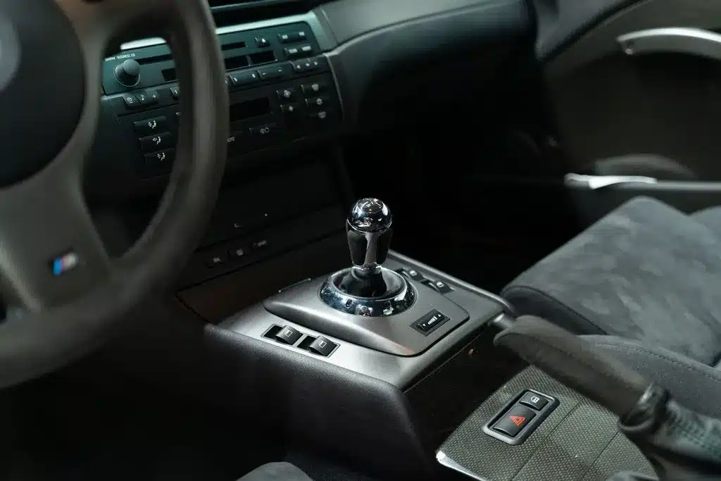 Nahaufnahme der Mittelkonsole und des Schalthebels im BMW M3 CSL E46 mit Alcantara-Interieur.