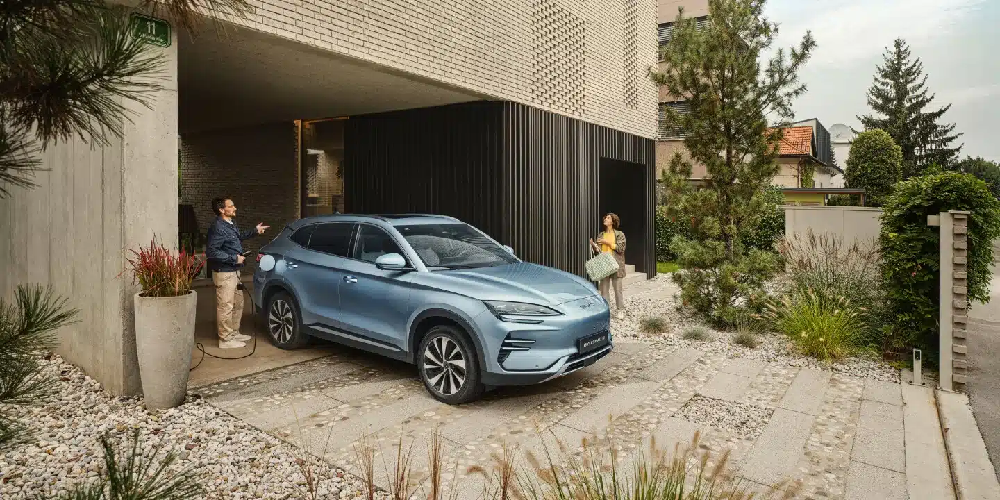 BYD SEAL U Elektro-SUV in hellblau beim Laden an einer Wallbox vor einem Wohnhaus