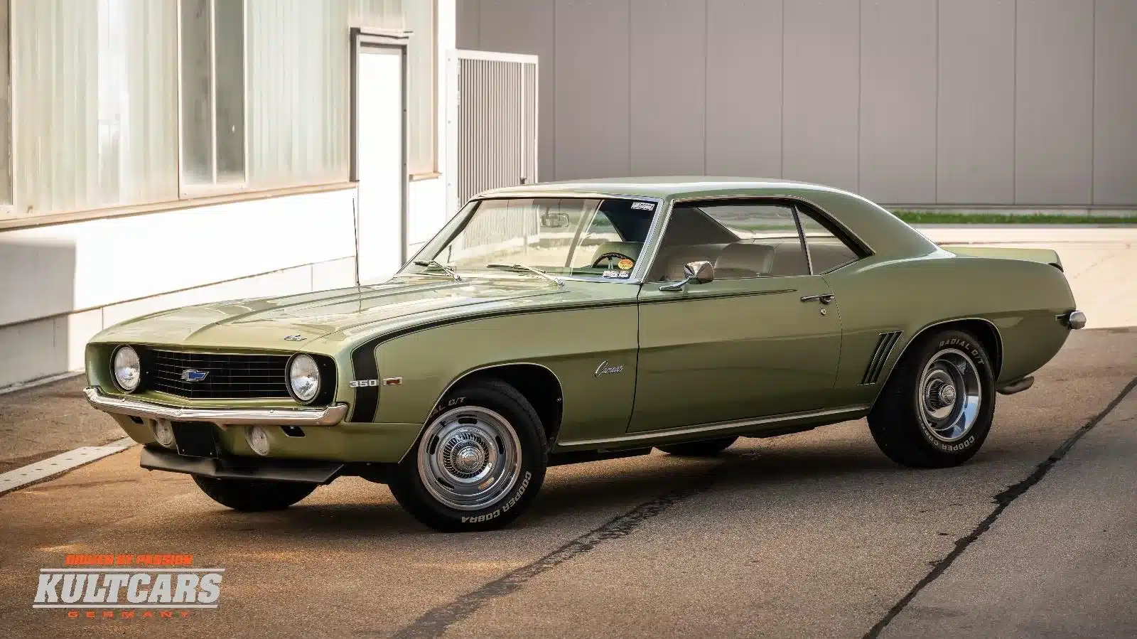 Chevrolet Camaro 350 V8 Coupé von 1969 in grün metallic, Seitenansicht vor moderner Halle