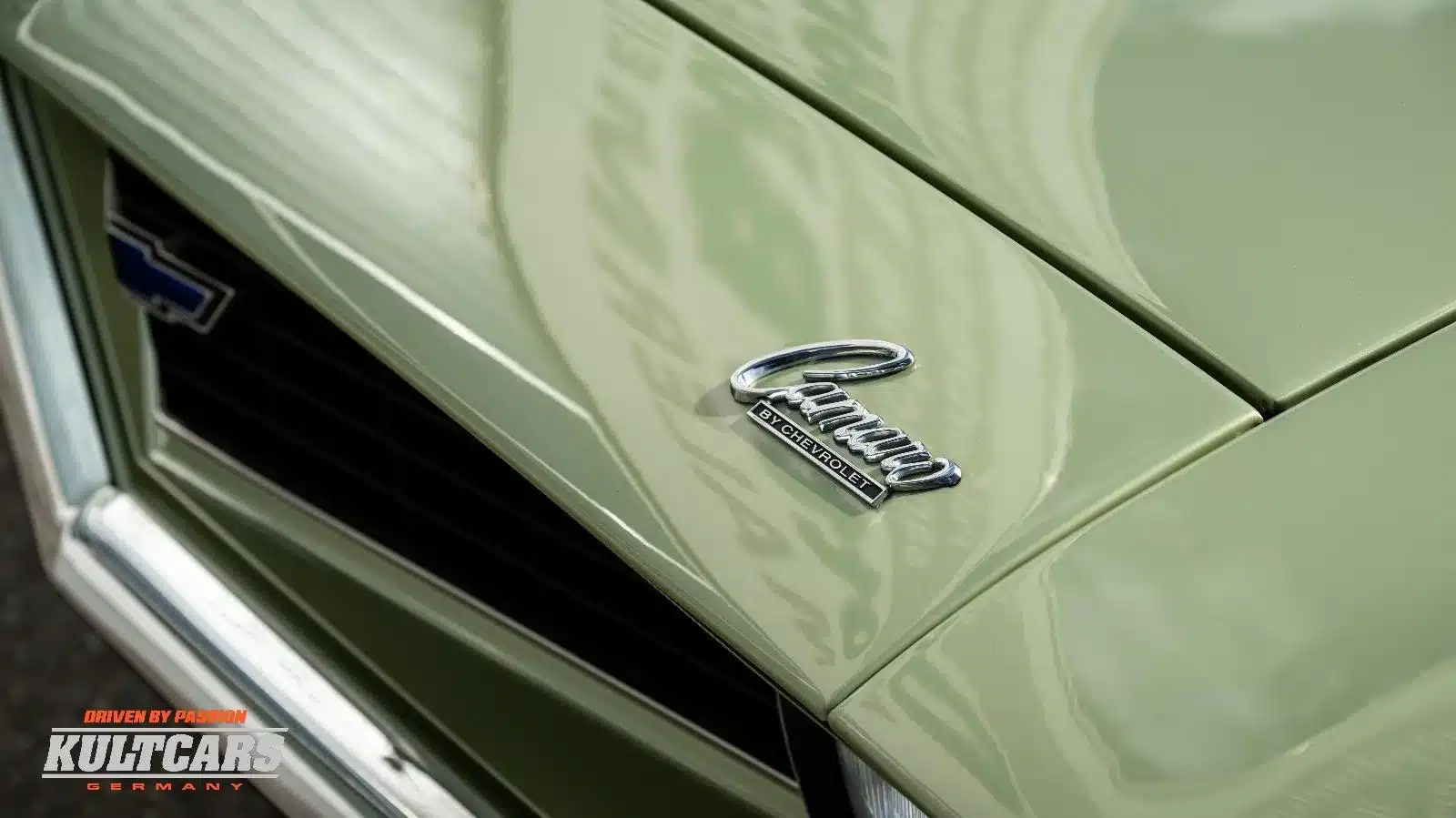 Nahaufnahme des Camaro-Logos auf der grünen Motorhaube eines klassischen Chevrolet Camaro 350 V8, Baujahr 1969.