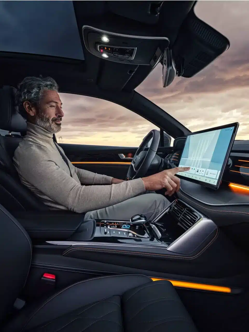 Fahrer im Innenraum des BYD Tang Elektro-SUV mit großem, drehbaren Zentraldisplay und Ambientebeleuchtung.