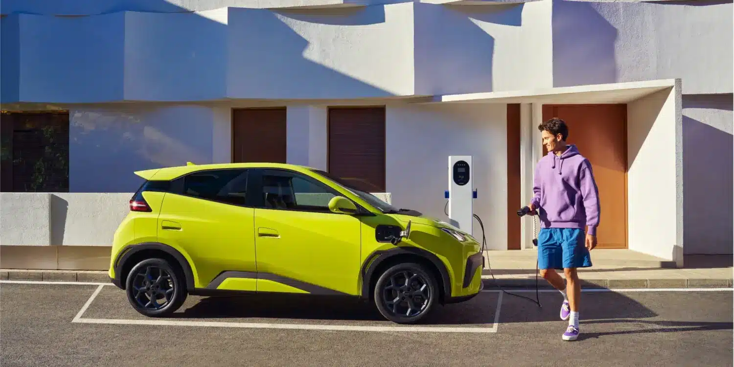 BYD Dolphin Surf Elektroauto in Gelb beim Ladevorgang an einer Wallbox vor einem modernen Gebäude.