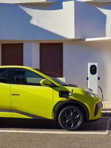 BYD Dolphin Surf Elektroauto in Gelb beim Ladevorgang an einer Wallbox vor einem modernen Gebäude.