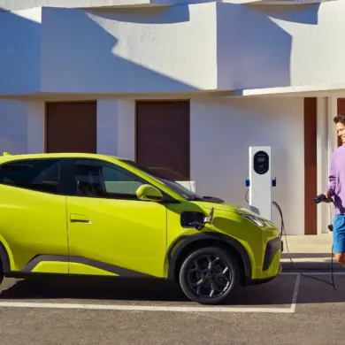 BYD Dolphin Surf Elektroauto in Gelb beim Ladevorgang an einer Wallbox vor einem modernen Gebäude.