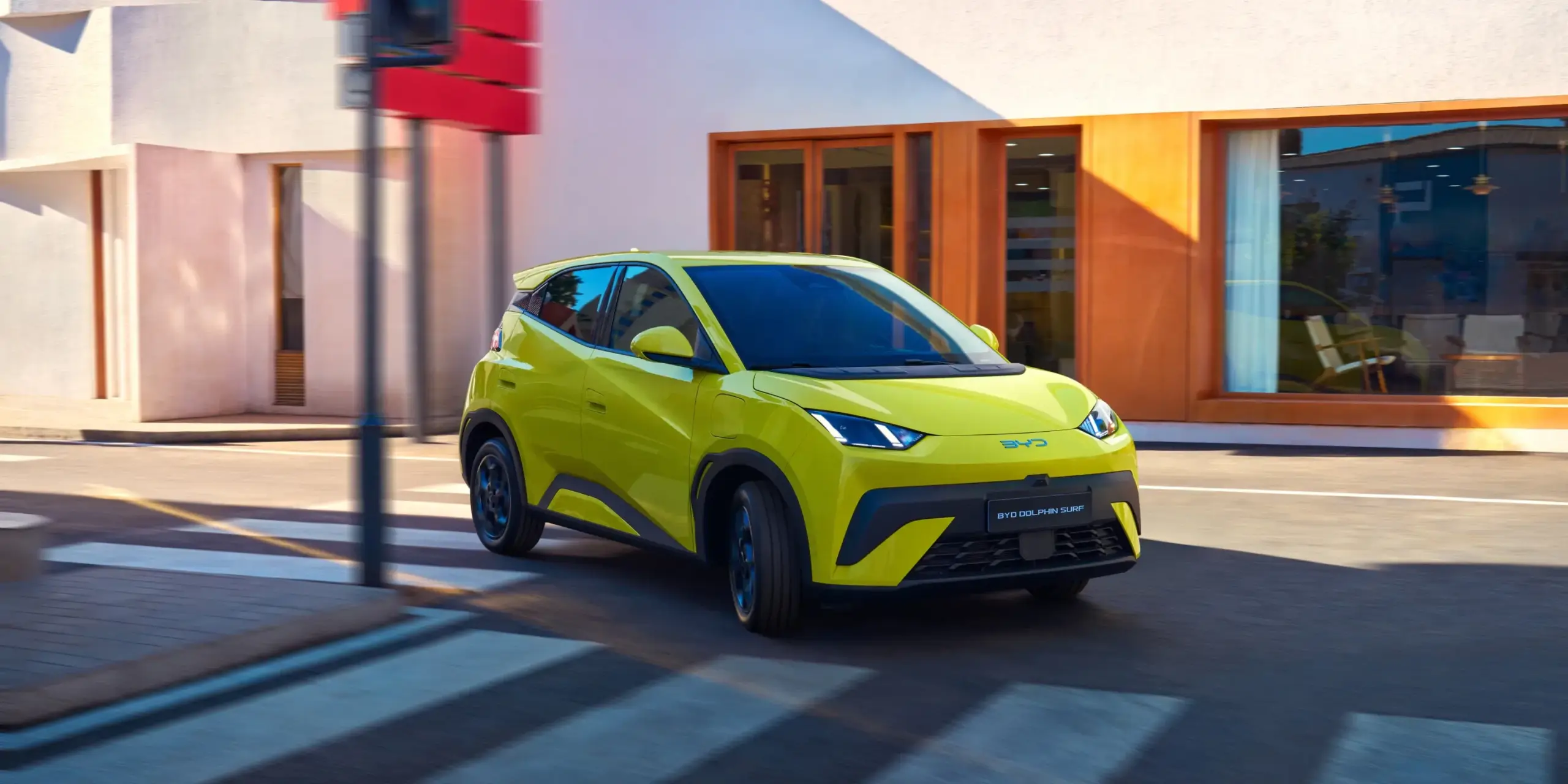 Gelber BYD Dolphin Surf fährt durch eine moderne Innenstadtumgebung.