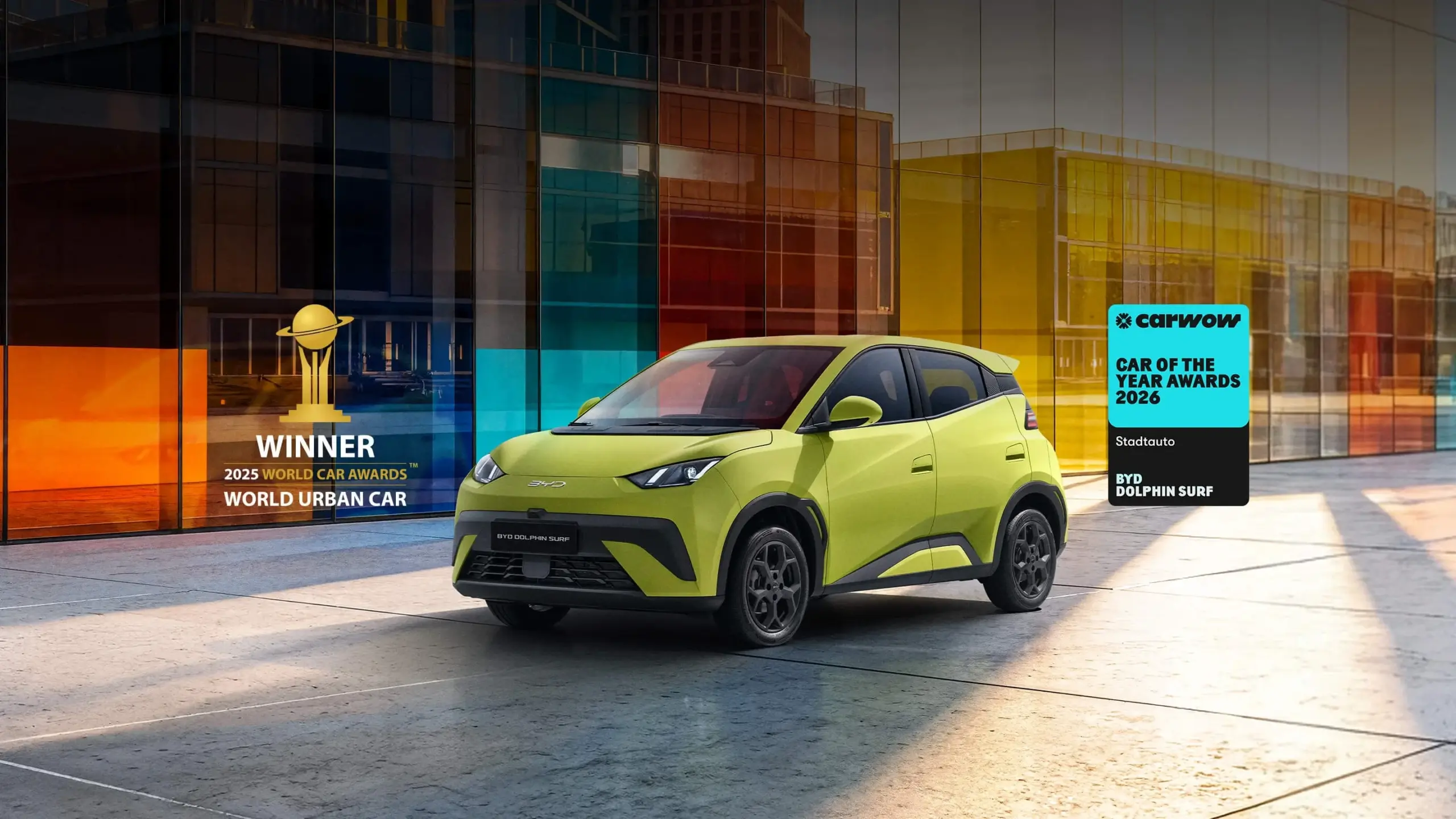 BYD Dolphin Surf in leuchtendem Grün vor Glasfassade, ausgezeichnet als World Urban Car 2025.