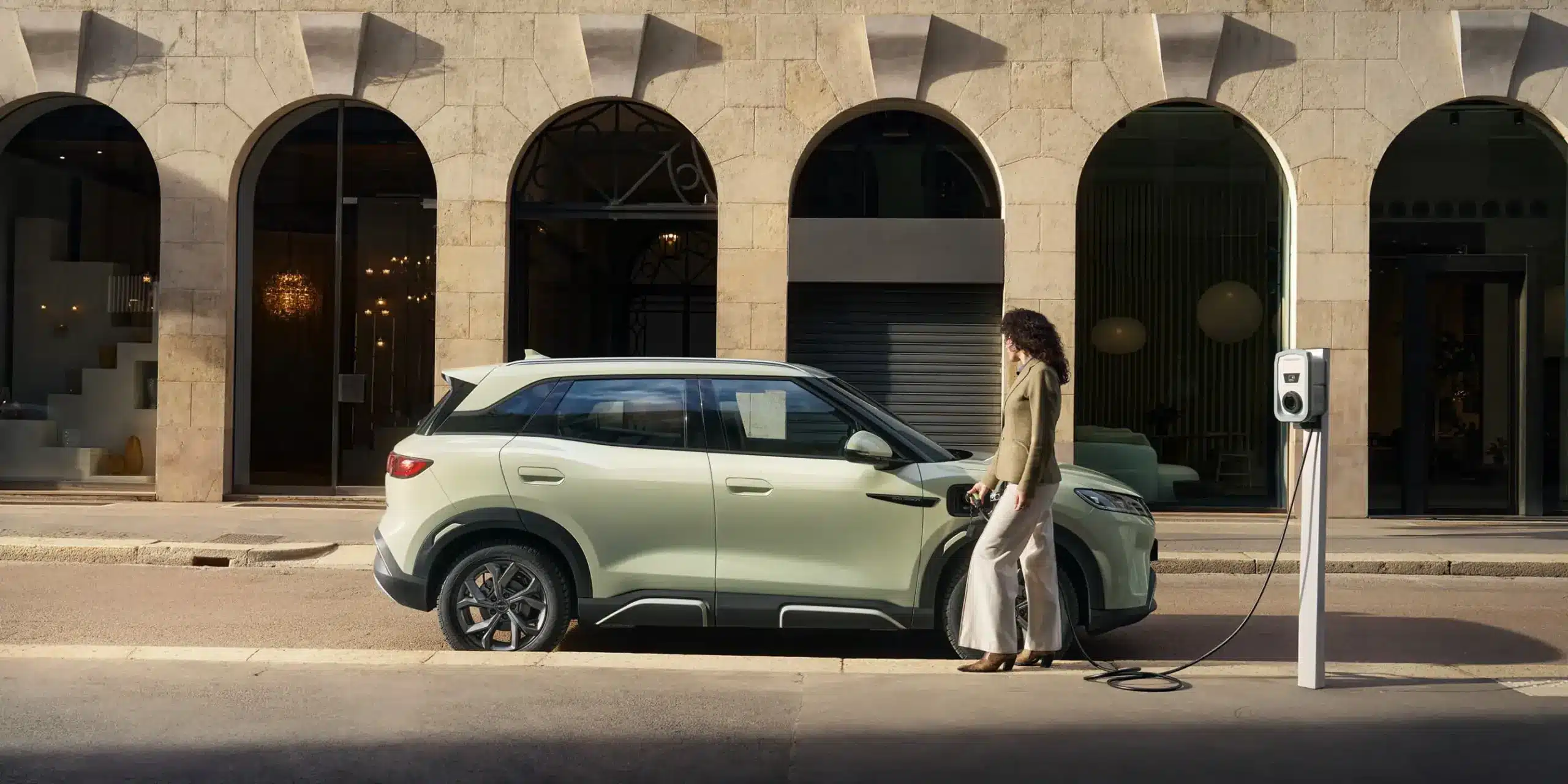 BYD ATTO 2 Elektroauto wird von einer Frau an einer öffentlichen Ladesäule in der Stadt geladen.