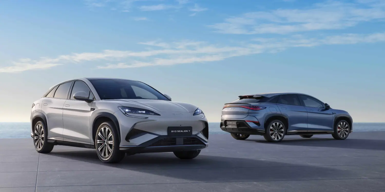 Zwei BYD SEALION 7 Elektro-SUVs stehen vor maritimer Kulisse auf einer Plattform, einer von vorn, einer von hinten.