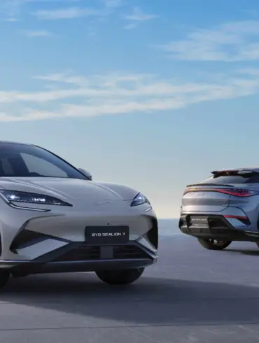 Zwei BYD SEALION 7 Elektro-SUVs stehen vor maritimer Kulisse auf einer Plattform, einer von vorn, einer von hinten.