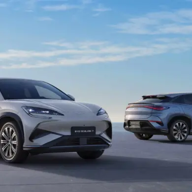 Zwei BYD SEALION 7 Elektro-SUVs stehen vor maritimer Kulisse auf einer Plattform, einer von vorn, einer von hinten.