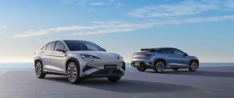 Zwei BYD SEALION 7 Elektro-SUVs stehen vor maritimer Kulisse auf einer Plattform, einer von vorn, einer von hinten.