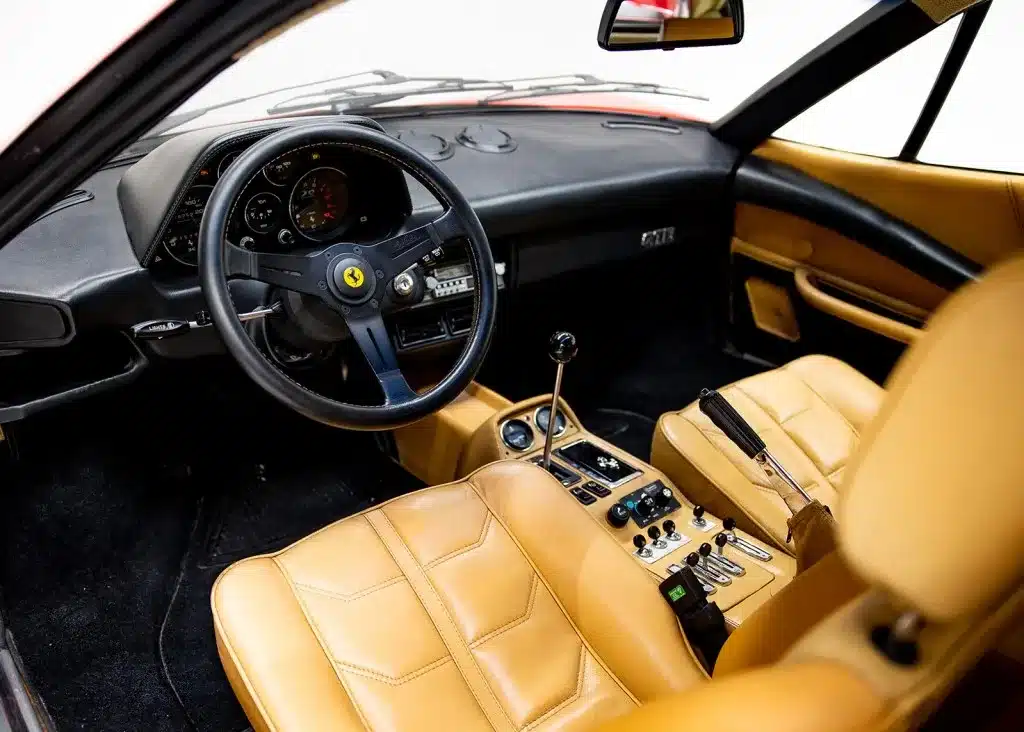 Innenraum eines Ferrari 208 GTB mit beigen Ledersitzen, sportlichem Lenkrad und manueller Schaltung