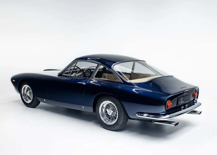 Ferrari 250 GT Lusso von hinten in Dunkelblau, Zweitürer mit markanter Panoramaheckscheibe und Drahtspeichenfelgen.