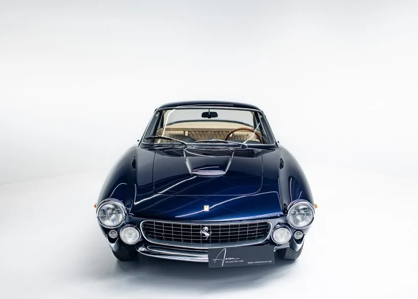 Frontansicht eines Ferrari 250 GT Lusso in dunkelblauer Farbe (Blu Pozzi) vor weißem Hintergrund, Oldtimer Coupé Baujahr 1964.