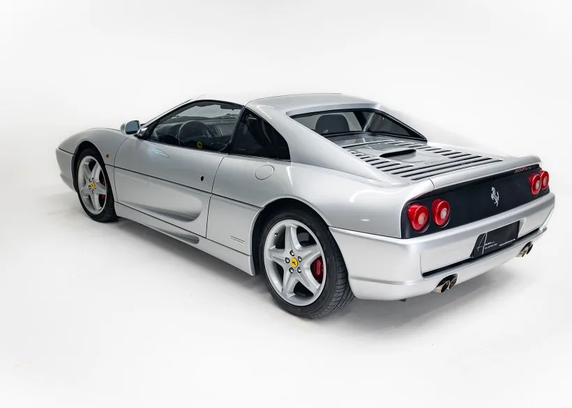Silberner Ferrari 355 F1 GTS von 1998, fotografiert schräg von hinten, mit sichtbaren Flying-Buttresses und Targadach.