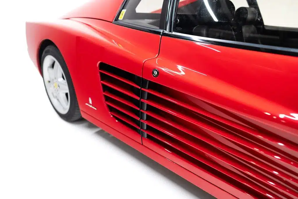 Seitenansicht eines roten Ferrari 512 TR mit markanten Lüftungskiemen vor dem Hinterrad