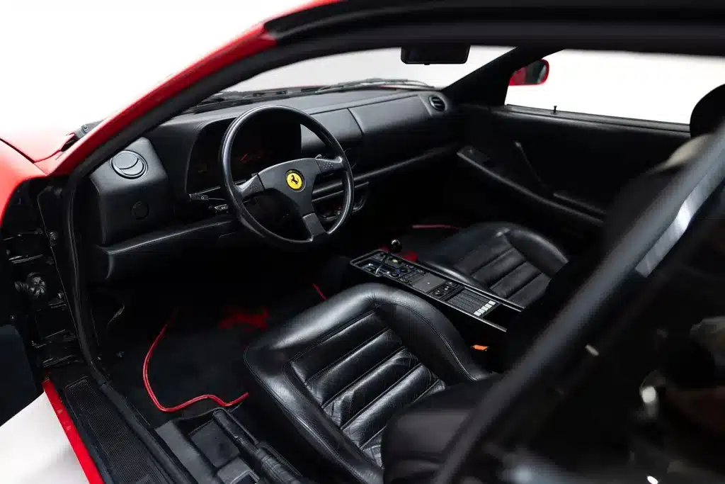 Innenraum eines Ferrari 512 TR von 1992 mit schwarzem Leder und typischem Ferrari-Lenkrad.