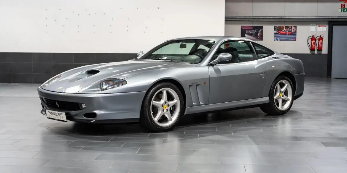 Silberner Ferrari 550 Maranello Handschalter, Frontmotor-V12-Coupé, ausgestellt in einer modernen Halle.