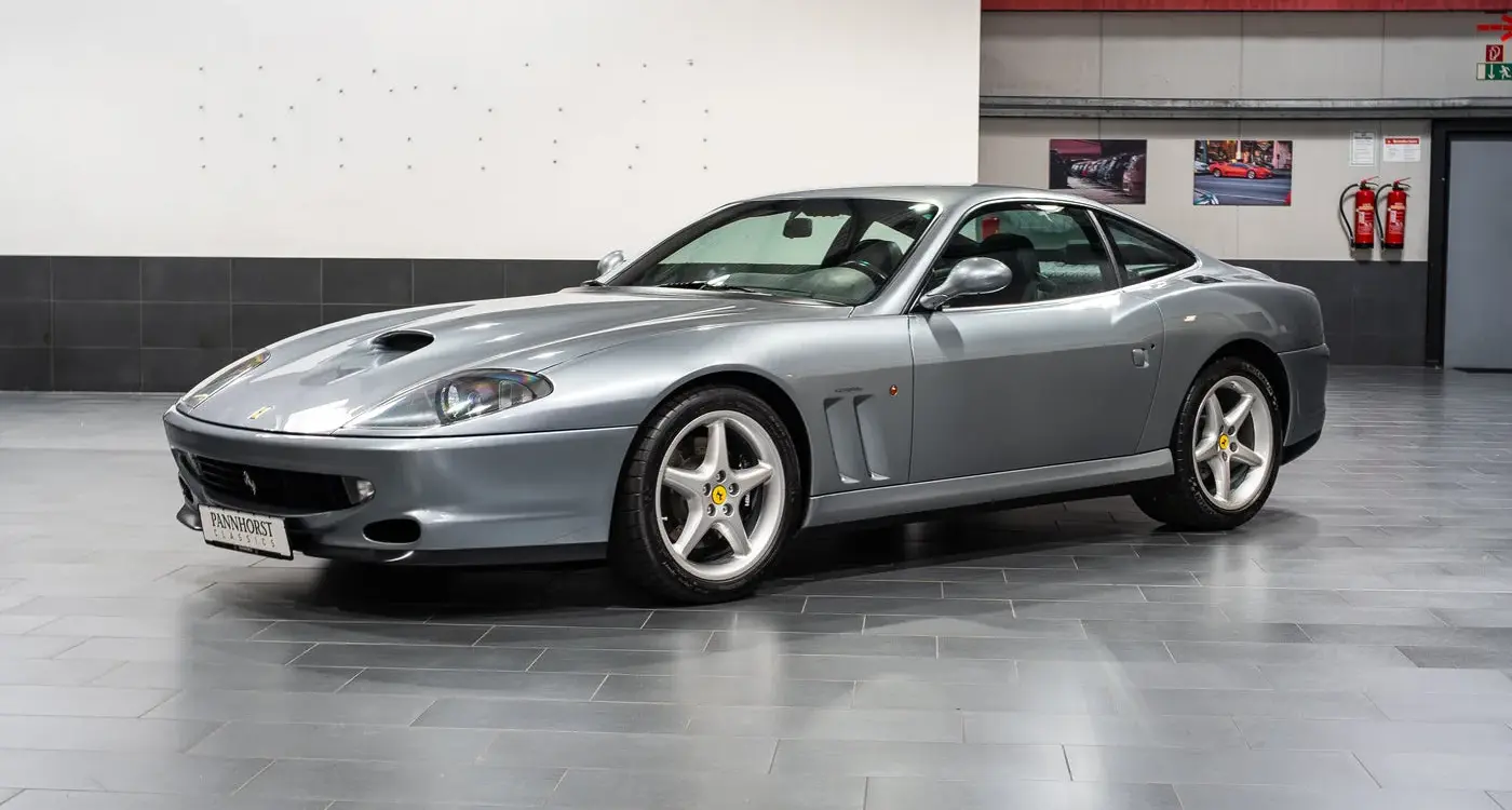 Silberner Ferrari 550 Maranello Handschalter, Frontmotor-V12-Coupé, ausgestellt in einer modernen Halle.