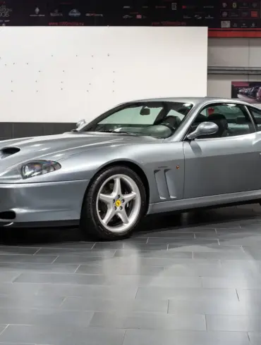Silberner Ferrari 550 Maranello Handschalter, Frontmotor-V12-Coupé, ausgestellt in einer modernen Halle.