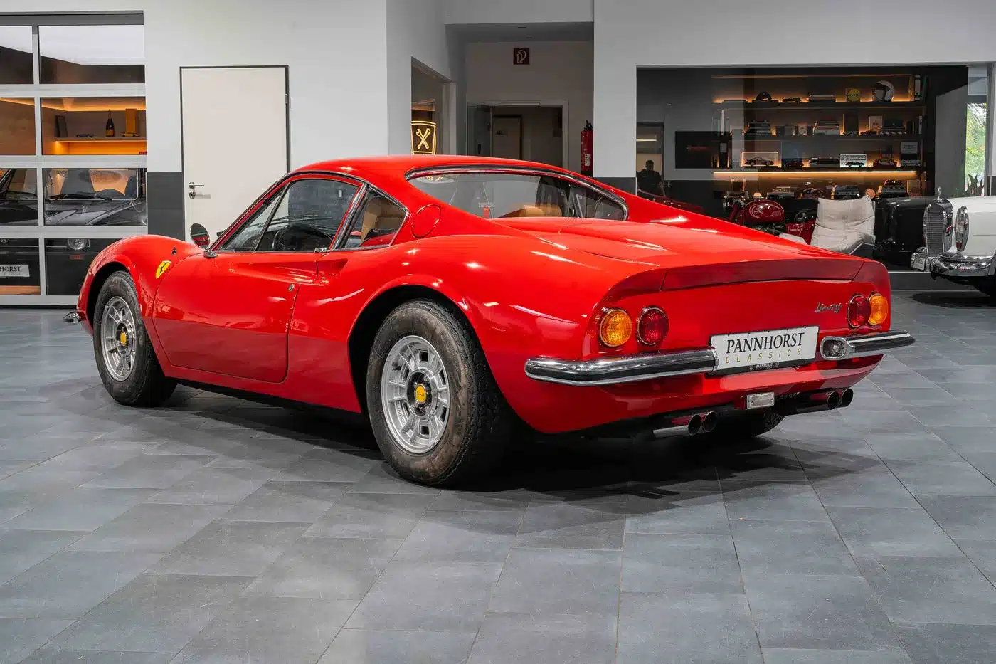 Roter Ferrari Dino 246 GT Typ M von hinten im Showroom, gut gepflegter Zustand, klassische Form.