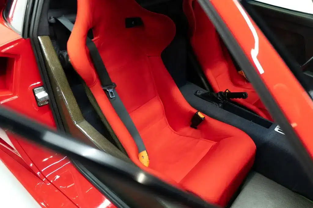 Innenraum des Ferrari F40 mit roten Schalensitzen aus Verbundwerkstoffen und Gurt.