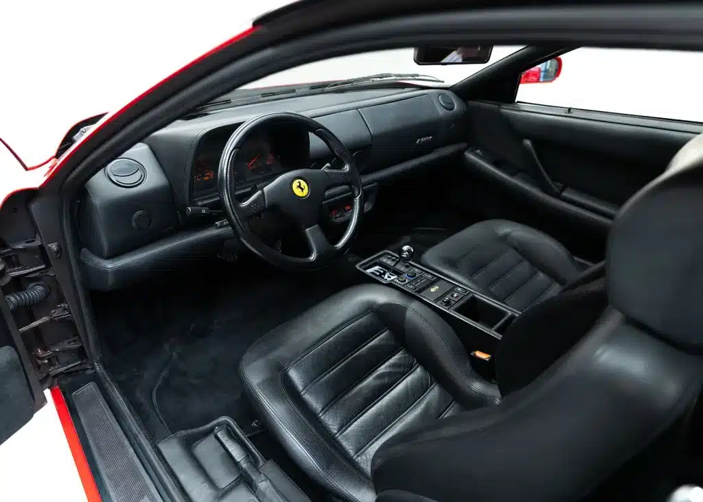 Ferrari F512 M Innenraum mit Handschaltgetriebe, schwarzes Leder, Blick auf Cockpit und Sitze.