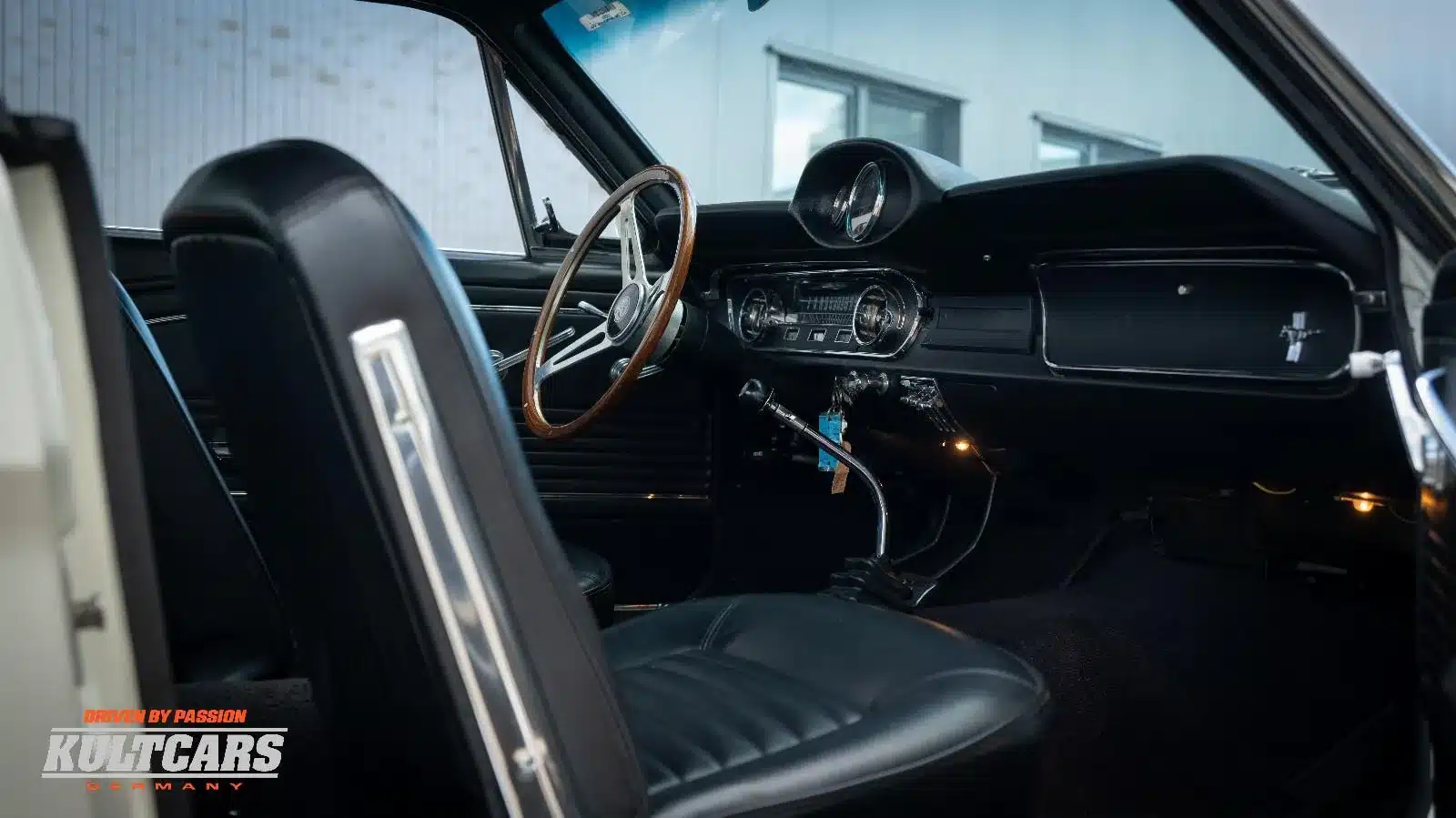 Blick auf das Cockpit eines Ford Mustang Shelby GT 350 Tribute von 1965 mit schwarzem Interieur, Holzlenkrad und klassischen Instrumenten