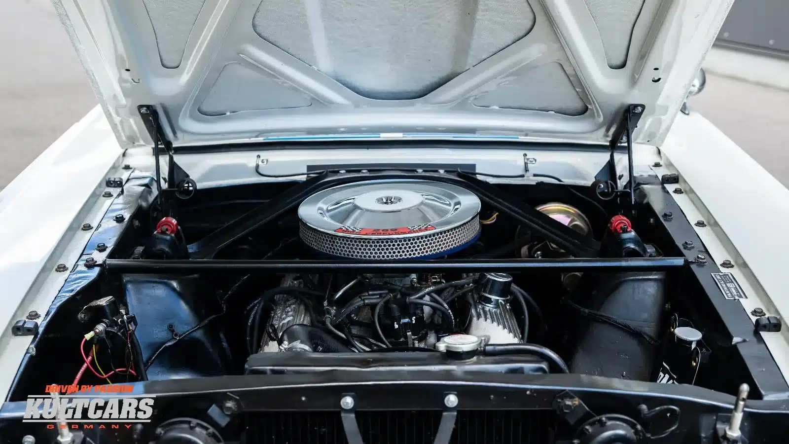 Motorraum eines 1965 Ford Mustang Shelby GT 350 Tribute mit sichtbarem 4,7-Liter-V8-Motor und verstärktem Strebenkreuz.