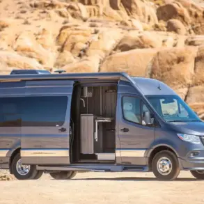 Grech Terreno-ion AWD Kastenwagen auf Mercedes-Benz Sprinter-Basis in der Wüste, seitliche Aussicht mit geöffneter Schiebetür.