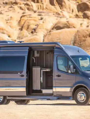 Grech Terreno-ion AWD Kastenwagen auf Mercedes-Benz Sprinter-Basis in der Wüste, seitliche Aussicht mit geöffneter Schiebetür.