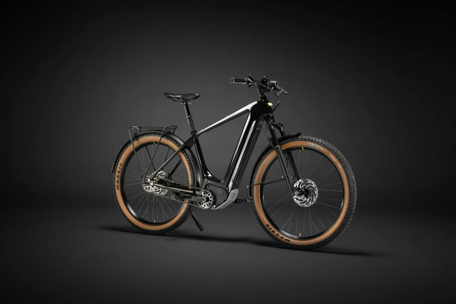 Schwarzes E-Tourenrad Heritage Style Escapade vor dunklem Hintergrund mit breiten Reifen, Schutzblechen und Gepäckträger.