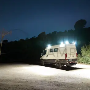 Iveco Daily 4x4 L3H2 Camper mit eingeschalteter Außenbeleuchtung bei Nacht auf offenem Gelände